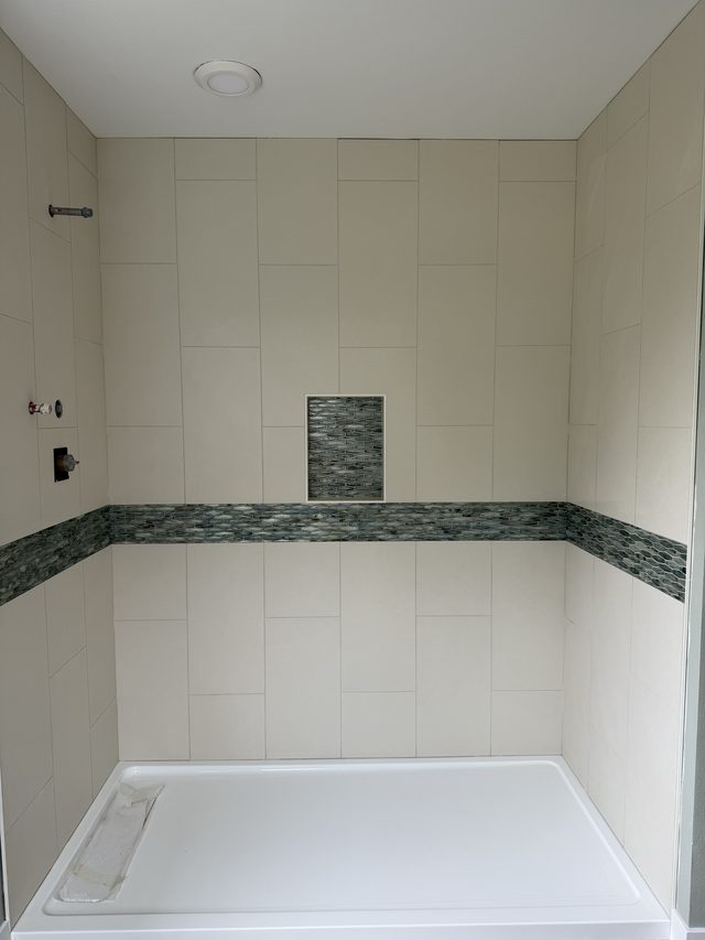 cream tile shower walls with mosaic accent strip and niche, white shower base