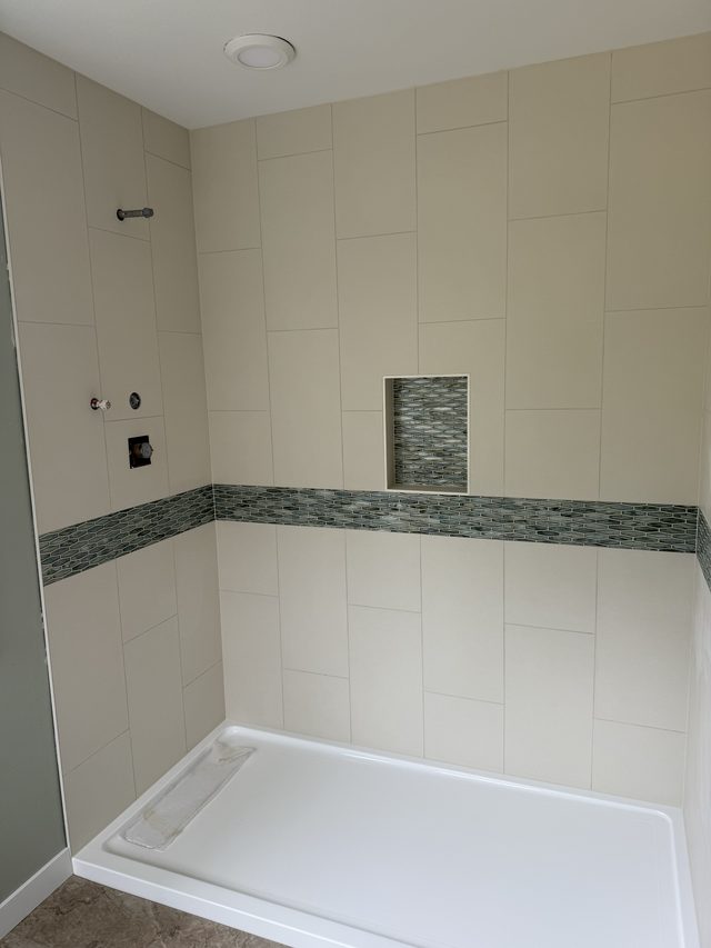 beige tile walk-in shower with mosaic band, niche and white shower pan