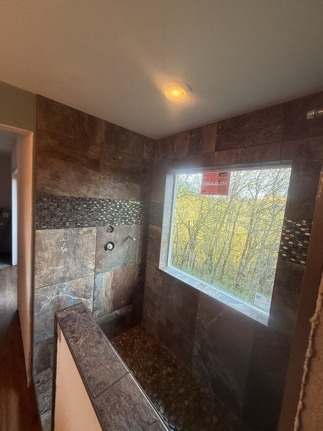 dark slate-tile walk-in shower with pebble accent and window