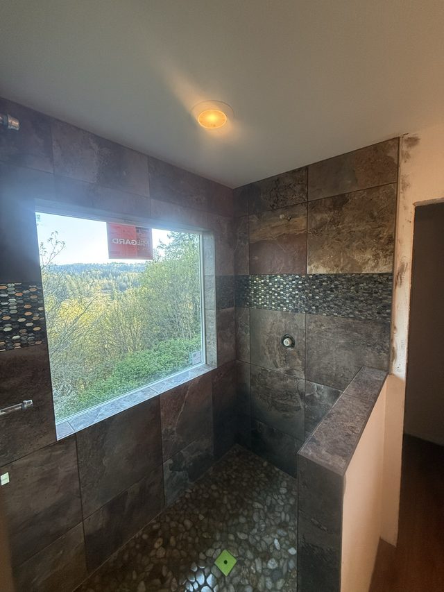stone-look tile shower with pebble floor and window