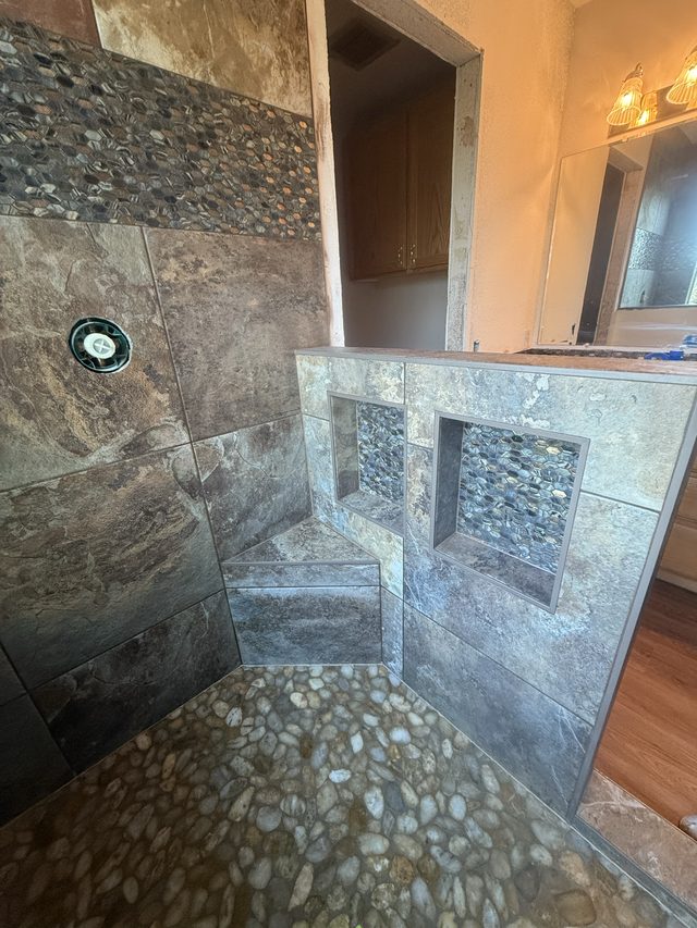 slate tile shower with pebble floor, bench and double niches