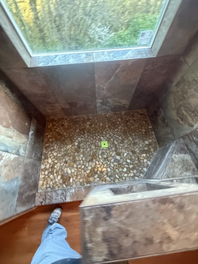 tiled shower with river-rock pebble floor and window