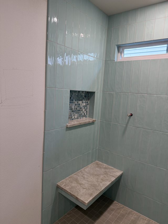 green glossy tile shower with mosaic niche and tiled bench
