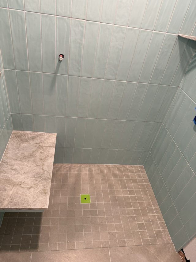green tile shower with tiled bench and mosaic floor