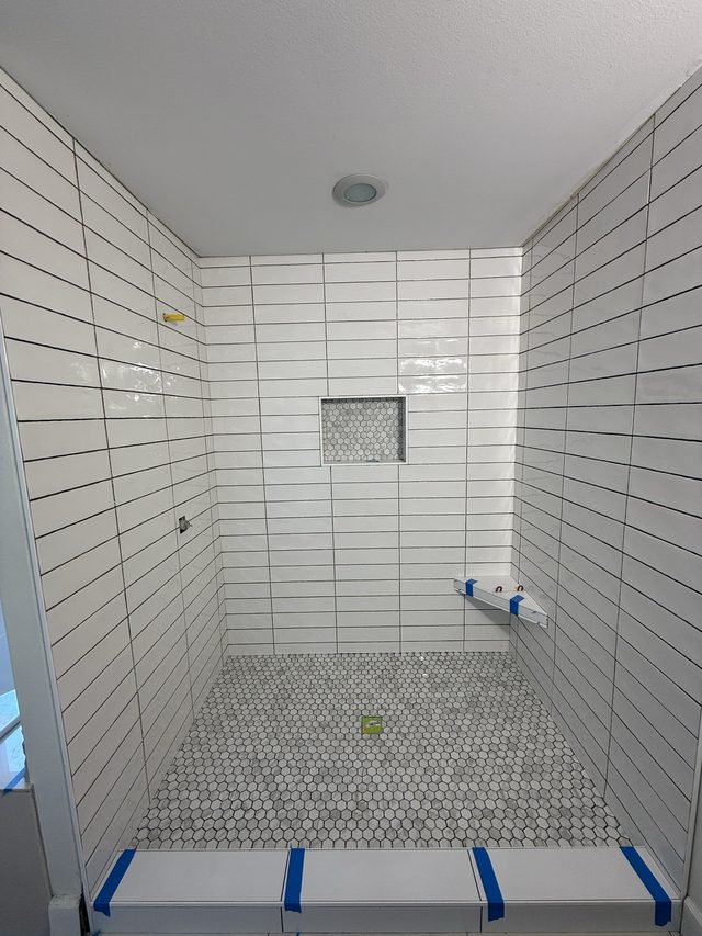 white tile walk-in shower with niche and penny-tile floor