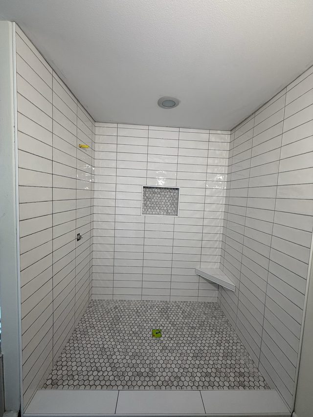 white tile walk-in shower, niche, corner bench, penny-tile floor