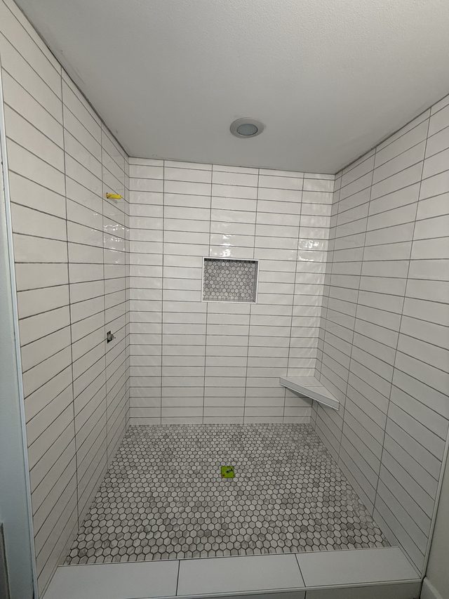 white tile walk-in shower with niche and hexagon floor