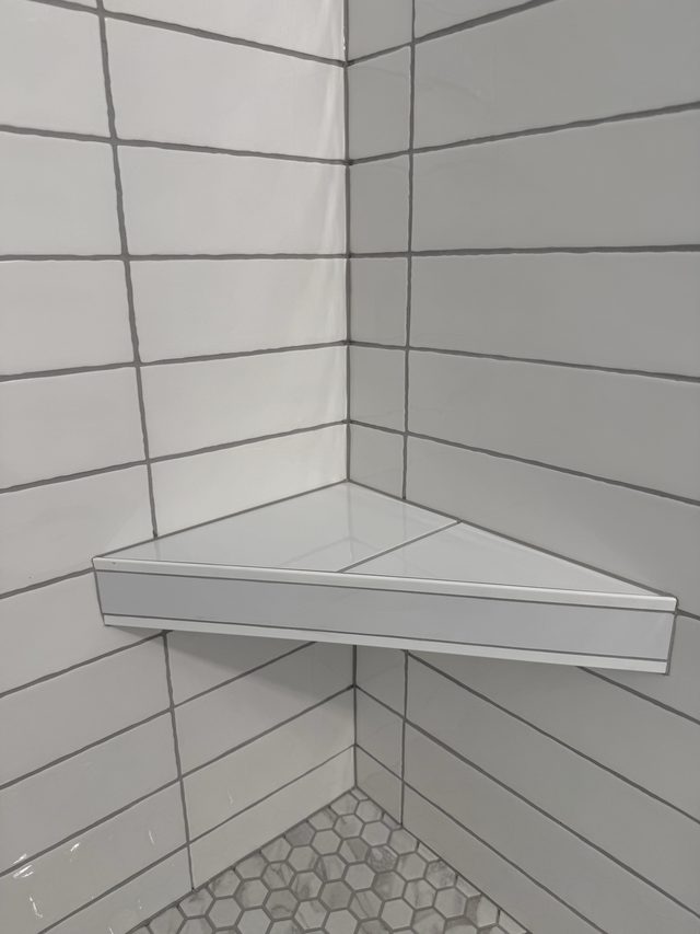 white tile shower corner shelf with hexagon floor