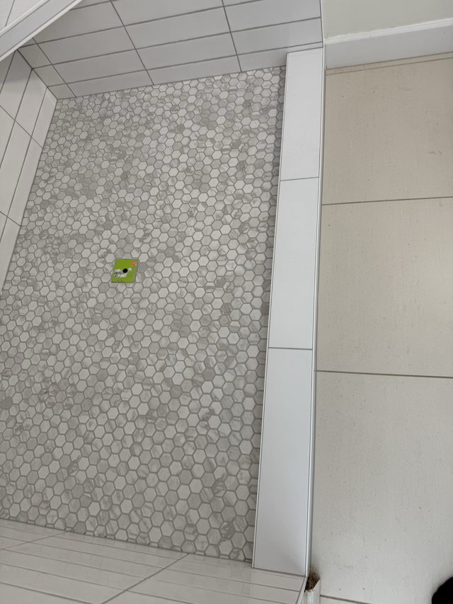 hexagon mosaic shower pan floor beside tiled bathroom floor