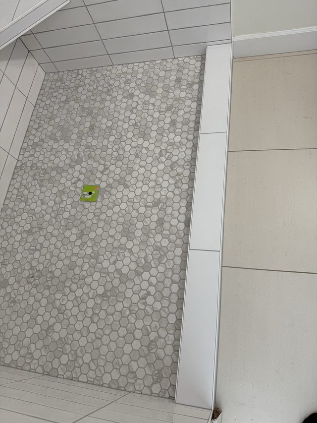 hexagon mosaic shower pan floor beside tiled bathroom floor