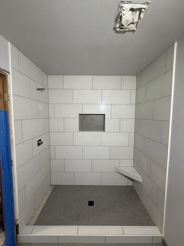 large white tile walk-in shower with niche, bench, shower valve