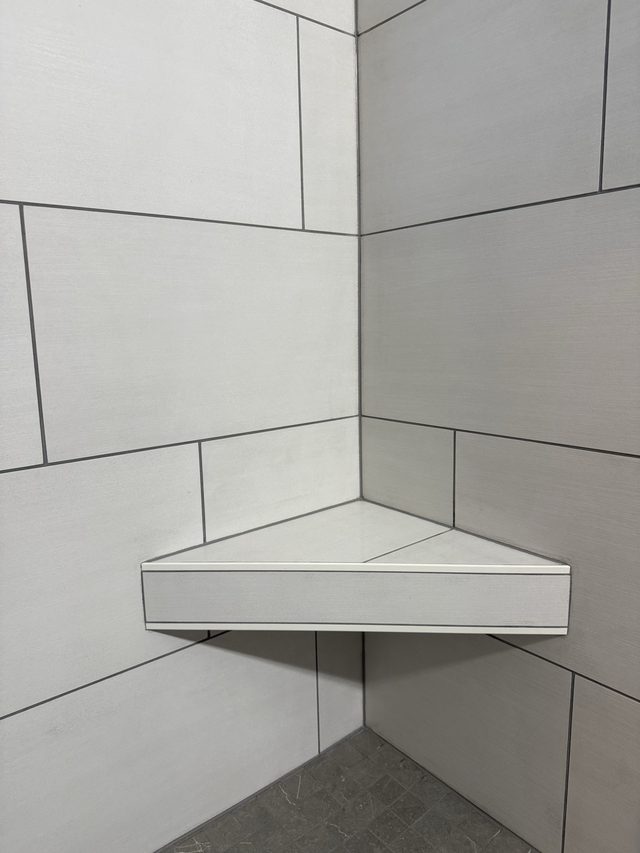corner shower shelf with white tile walls