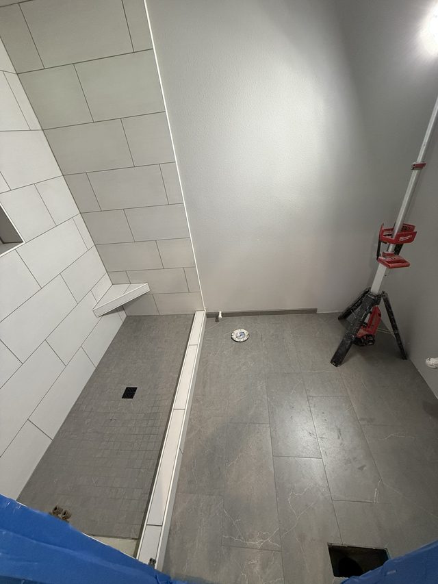 tiled shower wall and gray floor under construction