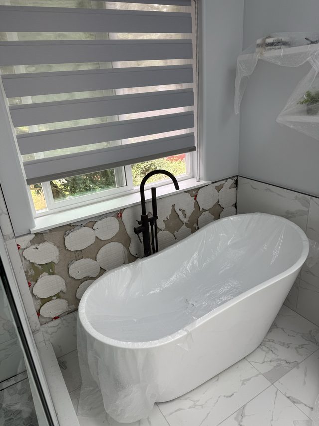 freestanding bathtub with floral tile backsplash