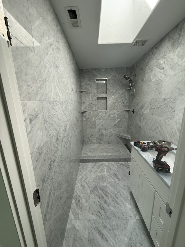marble-tile walk-in shower with niche and vanity