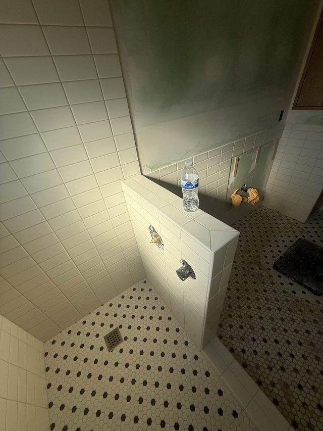 tiled shower with bench and B&W mosaic floor