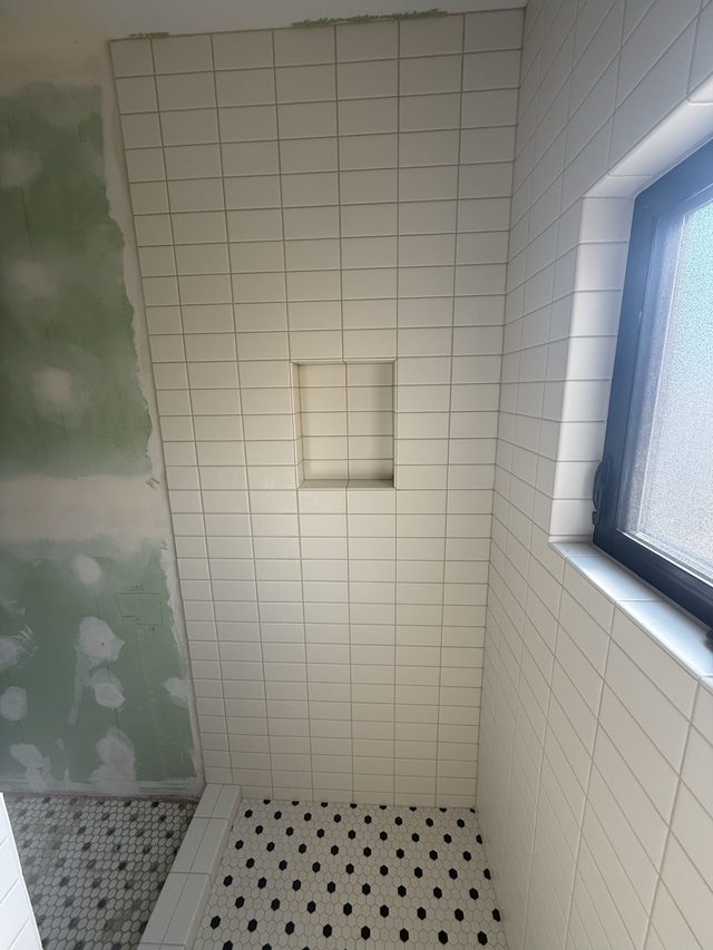 tiled shower with niche, window, mosaic floor