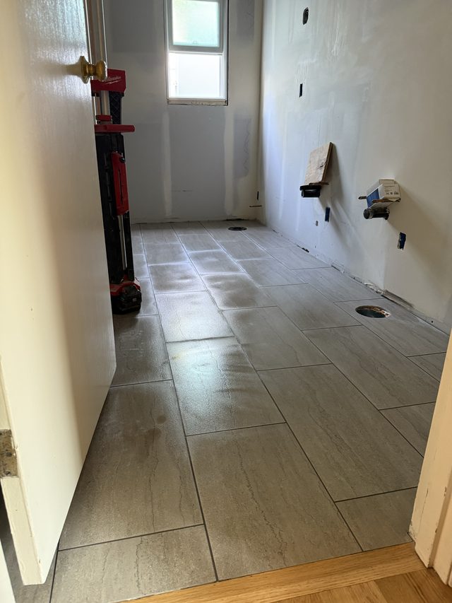 bathroom under construction with tiled floor and plumbing rough-ins