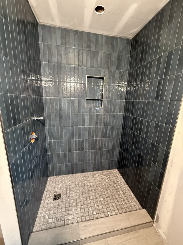 blue tile walk-in shower with niche and mosaic floor