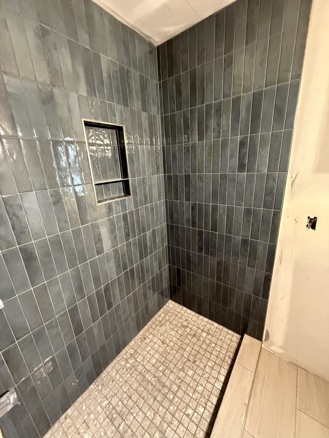 blue-gray tiled shower with niche and mosaic floor