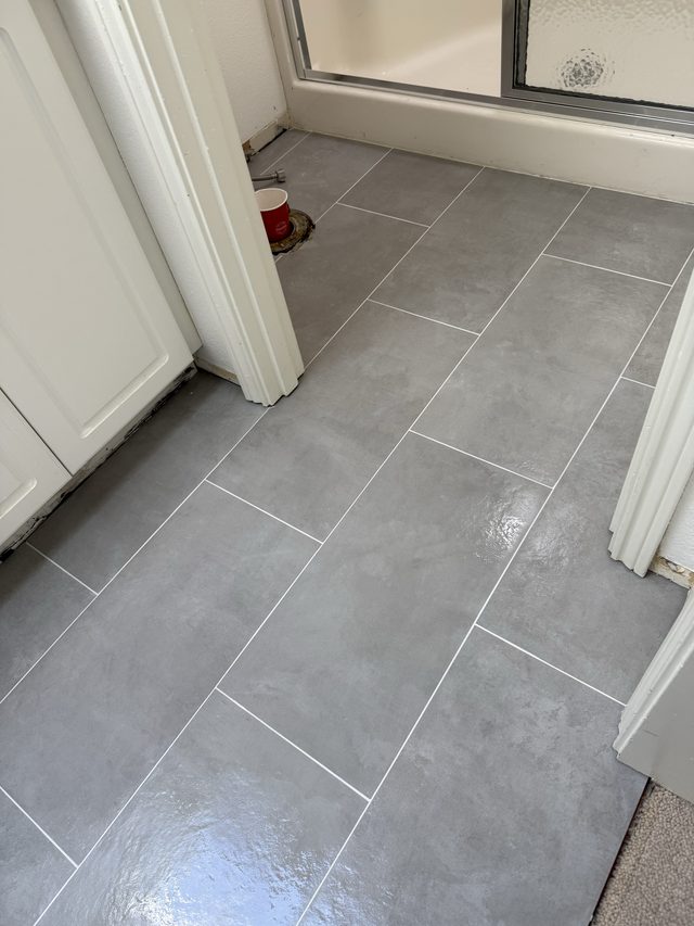 gray tile floor beside shower glass door enclosure