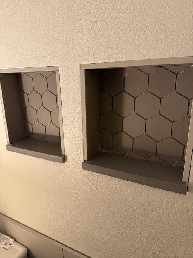 two recessed shower niches with hexagon tile backing