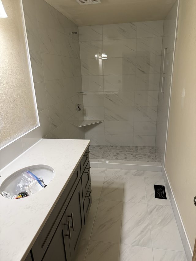 marble-tile walk-in shower with vanity and tiled floor