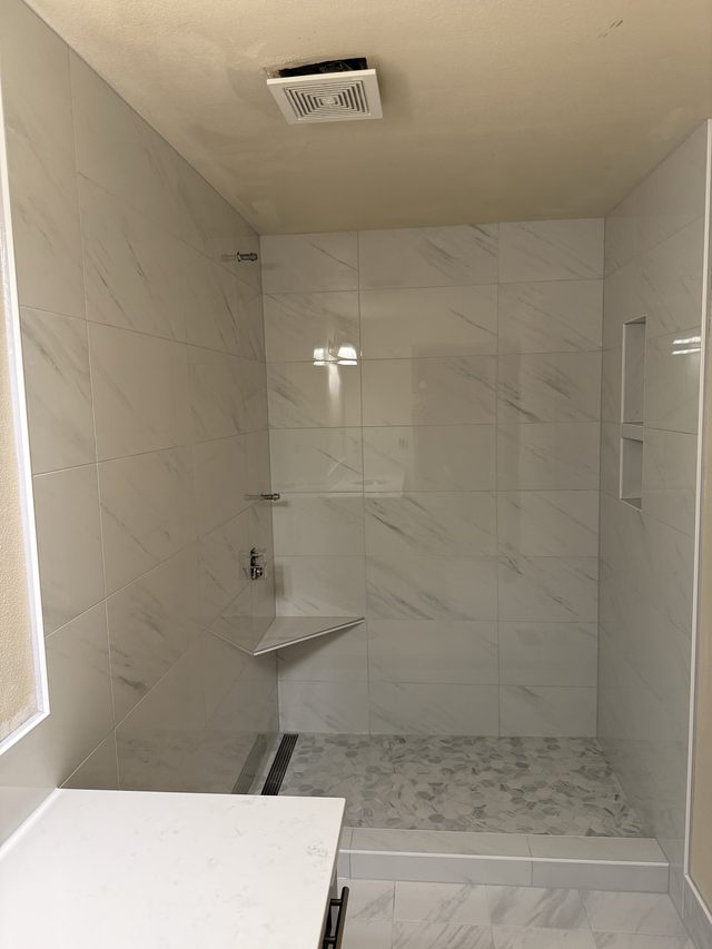 marble-tile walk-in shower with niche and linear drain