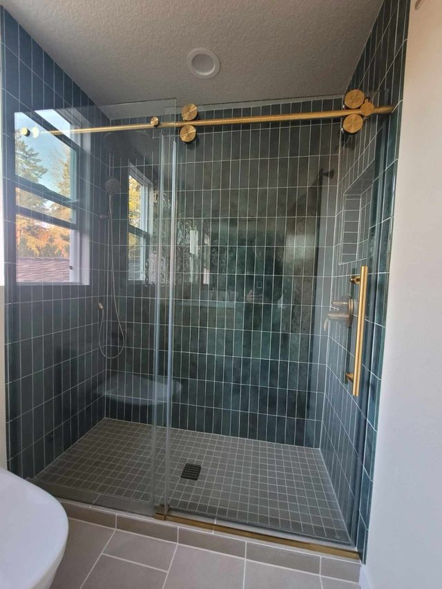 teal vertical-tile walk-in shower with gold fixtures and bench