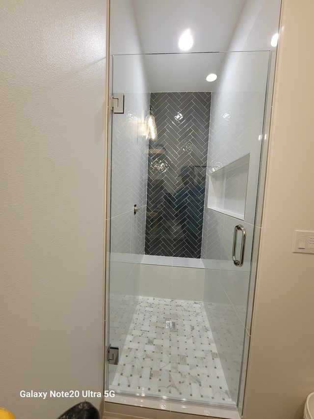 shower with blue herringbone accent tile and marble basketweave floor