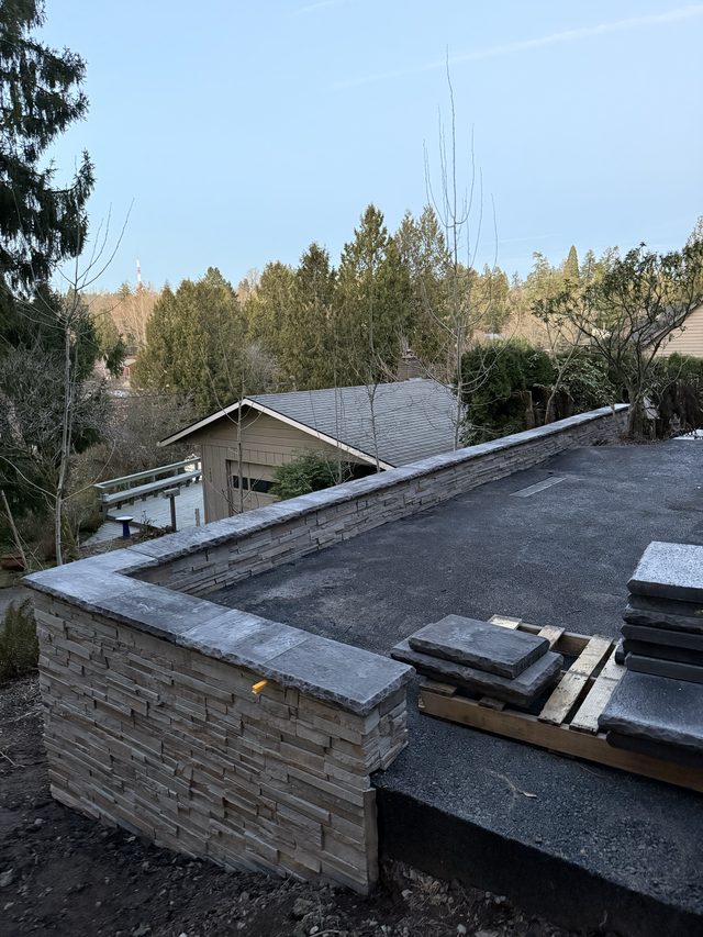stone-capped outdoor wall with garage and trees in background