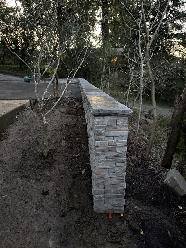 stacked-stone outdoor wall along driveway with dirt bed
