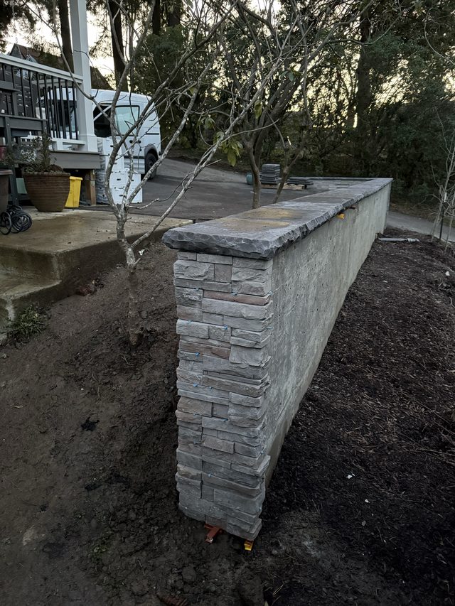 stacked-stone outdoor wall with van and trees
