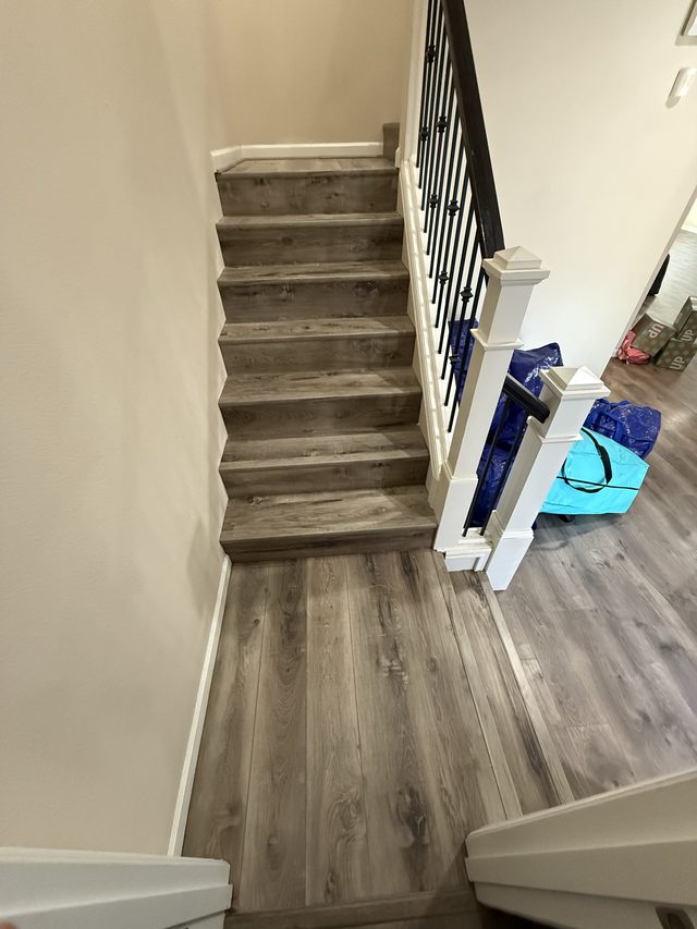 staircase with wood-look treads, railing and plank landing floor