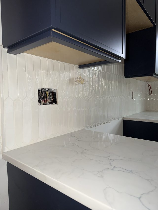 white picket backsplash, navy cabinets, marble countertop