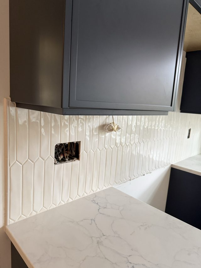 white picket backsplash, dark cabinets, marble countertop