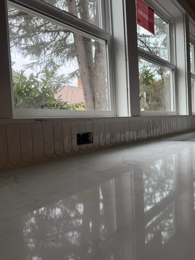 white marble countertop with picket backsplash by windows