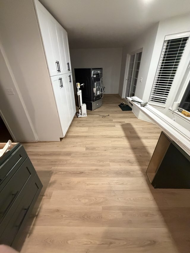 kitchen under renovation with tall white pantry cabinets, green base cabinet, appliance, vinyl plank floor