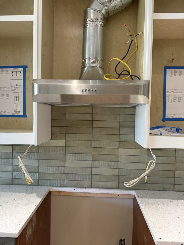 stainless range hood over green tile backsplash, kitchen
