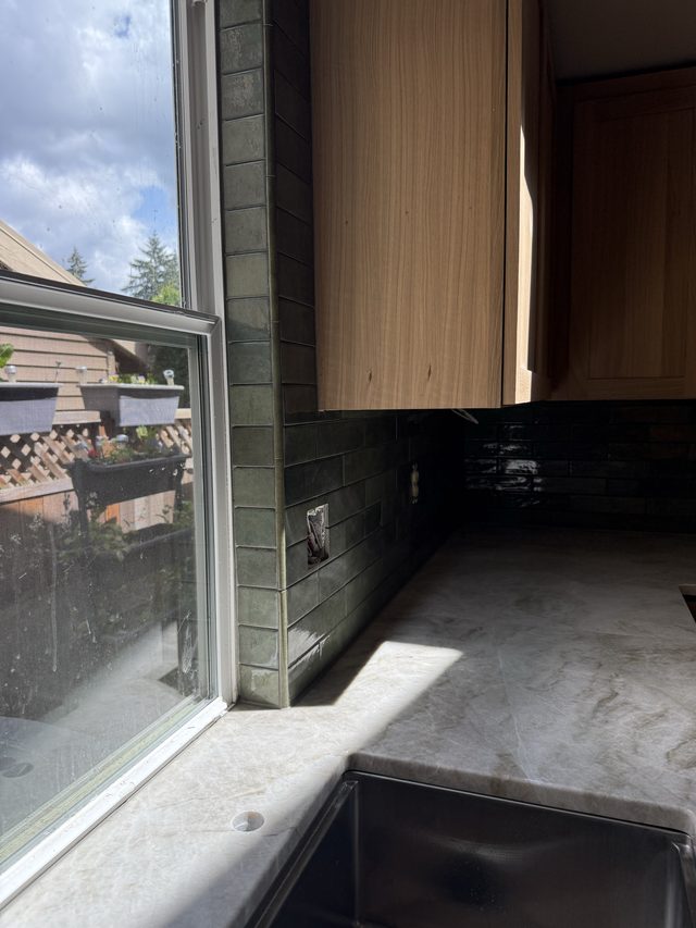 kitchen counter with sink, dark backsplash tile and cabinets
