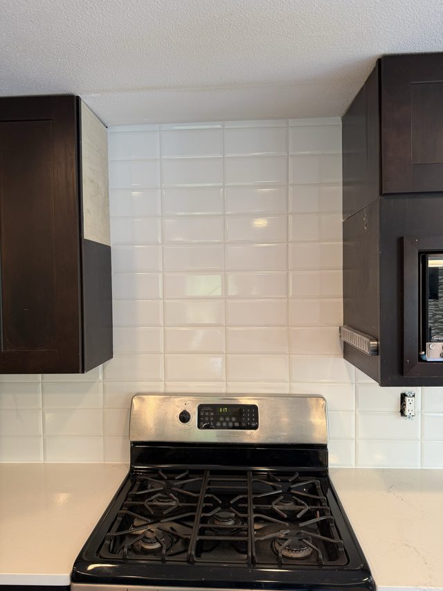 white subway backsplash behind gas range