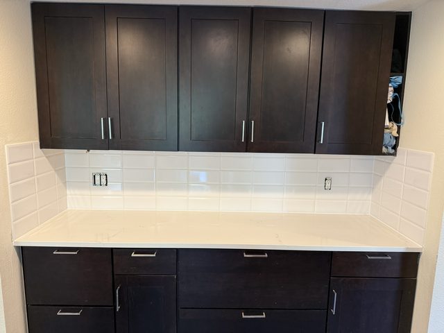 dark upper cabinets, white backsplash, quartz counter
