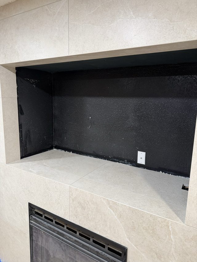 tiled fireplace niche with black interior, firebox vent below