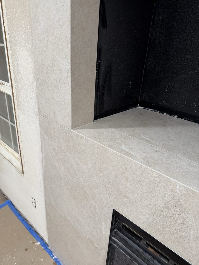 corner of tiled fireplace surround beside window