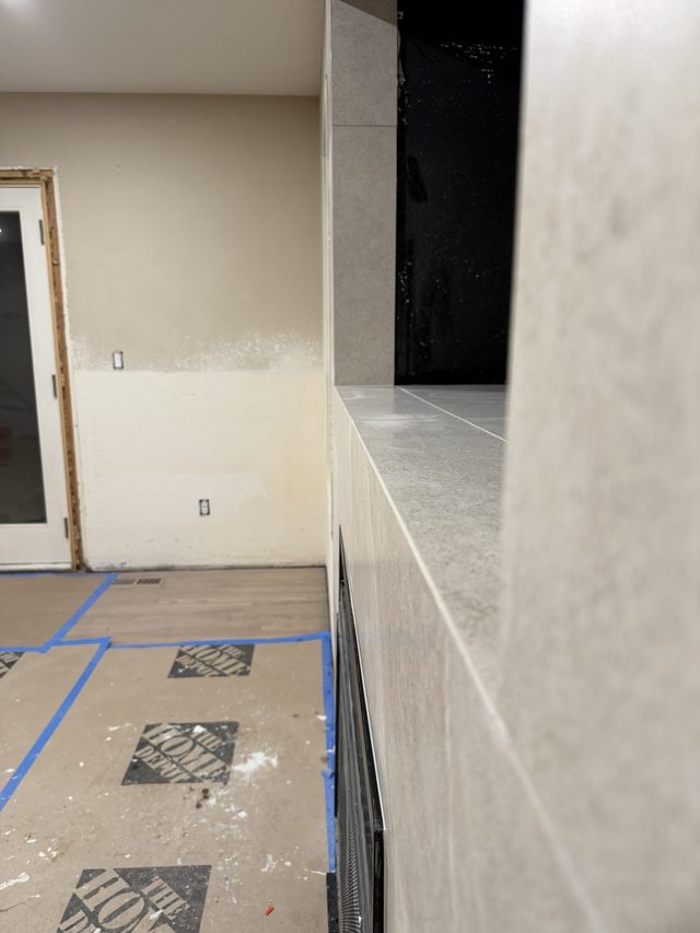 side of tiled fireplace surround, firebox vent and room beyond