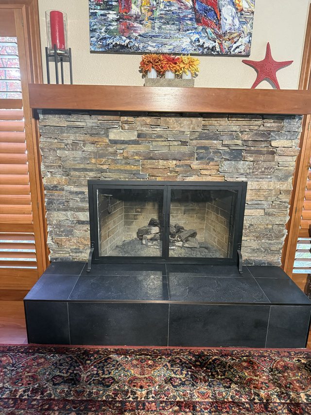 stacked stone fireplace with black tile hearth